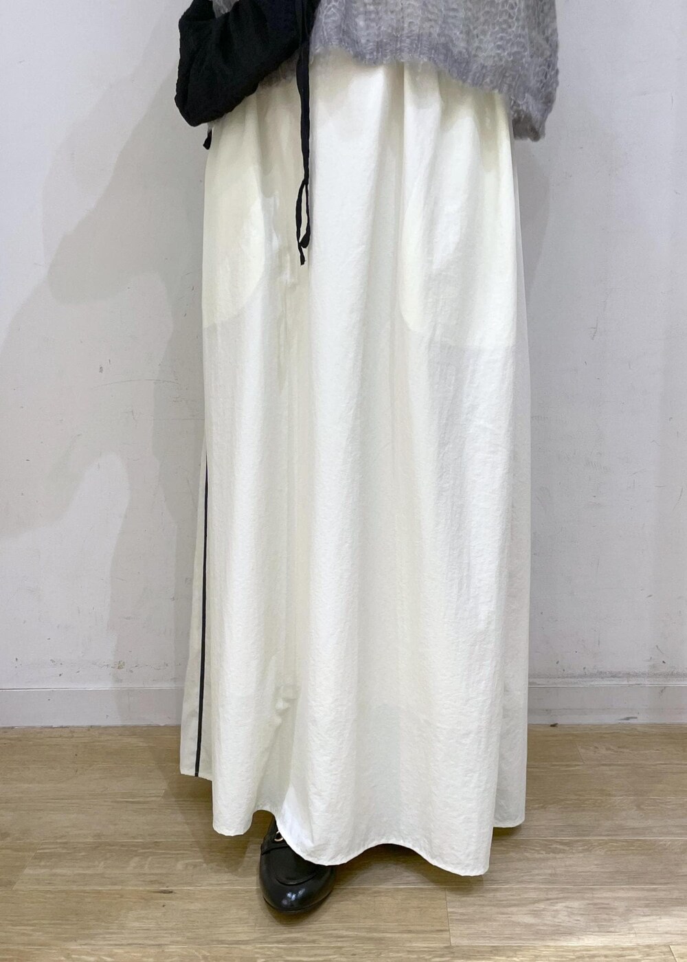 ブラック系のローファー、ホワイト系のスカート、グレー系のニット/セーターを着用したレディースの秋コーディネートの6枚目の写真