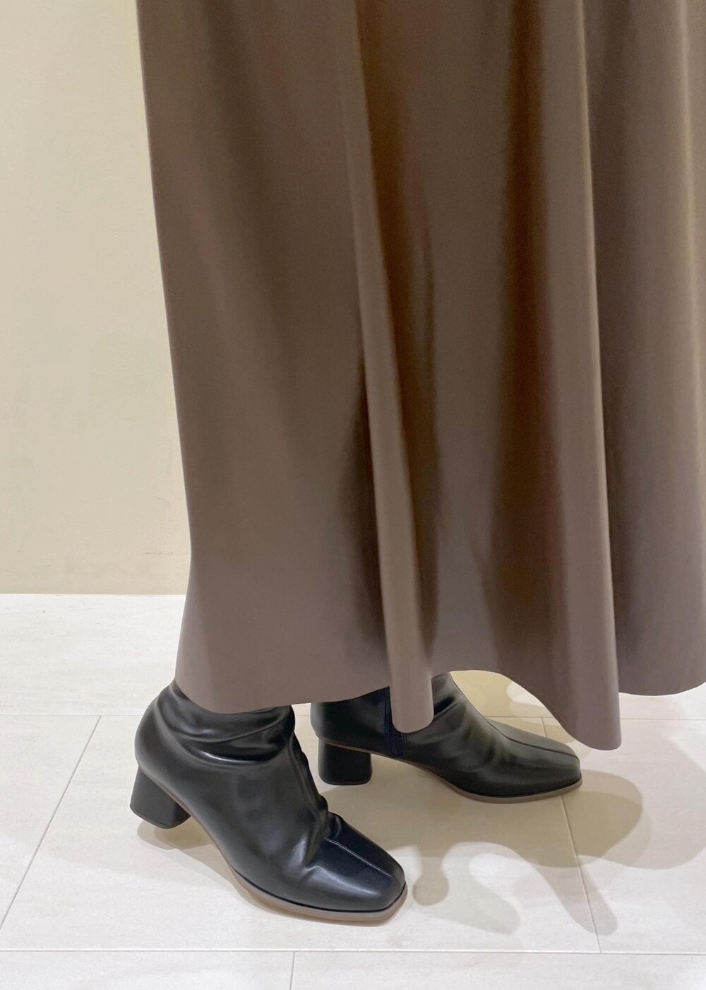 ブラック系のショルダーバッグ、ブラウン系のスカート、ホワイト系のカーディガン/ボレロを着用したレディースの秋コーディネートの9枚目の写真