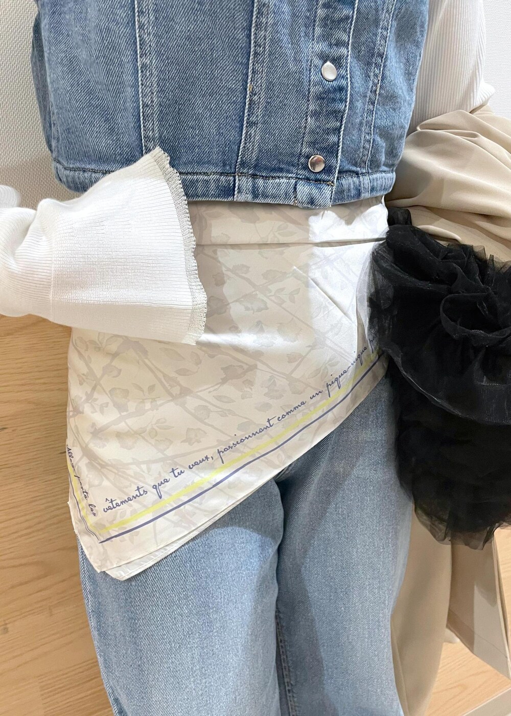 ブルー系のベスト、ホワイト系のニット/セーター、ベージュ系のトレンチコートを着用したレディースの春コーディネートの6枚目の写真