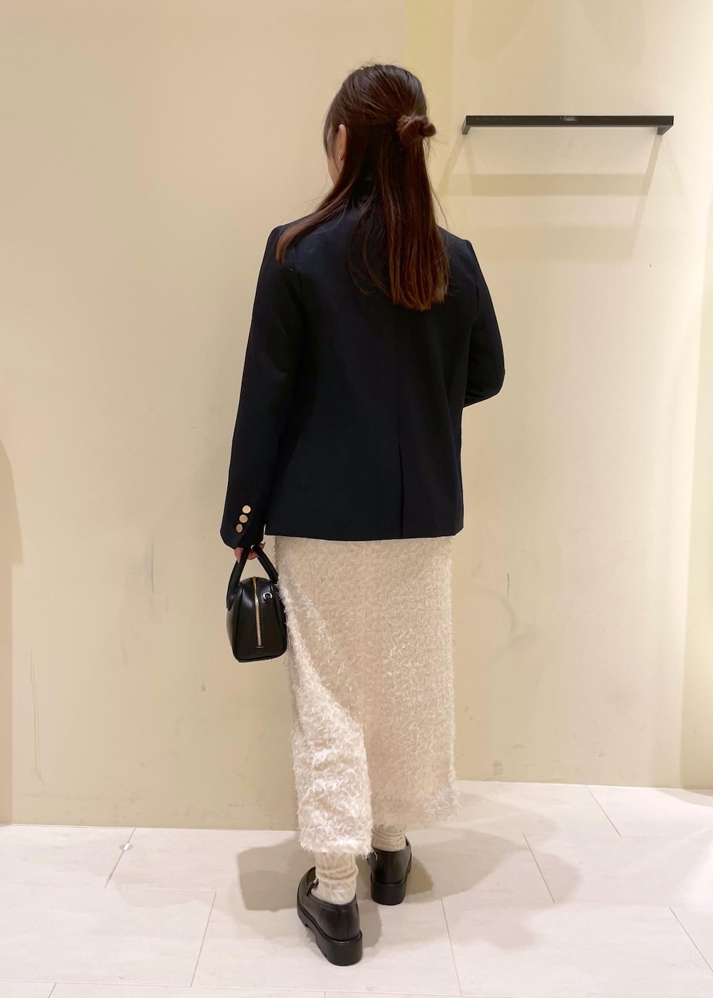 ブラック系のショルダーバッグ、ホワイト系のスカート、ブラック系のローファーを着用したレディースの秋コーディネートの2枚目の写真