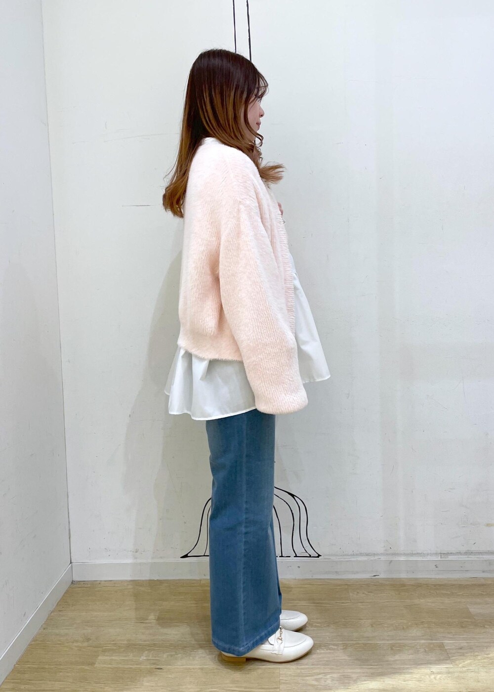 ブルー系のデニムパンツ、ホワイト系のショルダーバッグ、ホワイト系のパンプスを着用したレディースの冬コーディネートの3枚目の写真