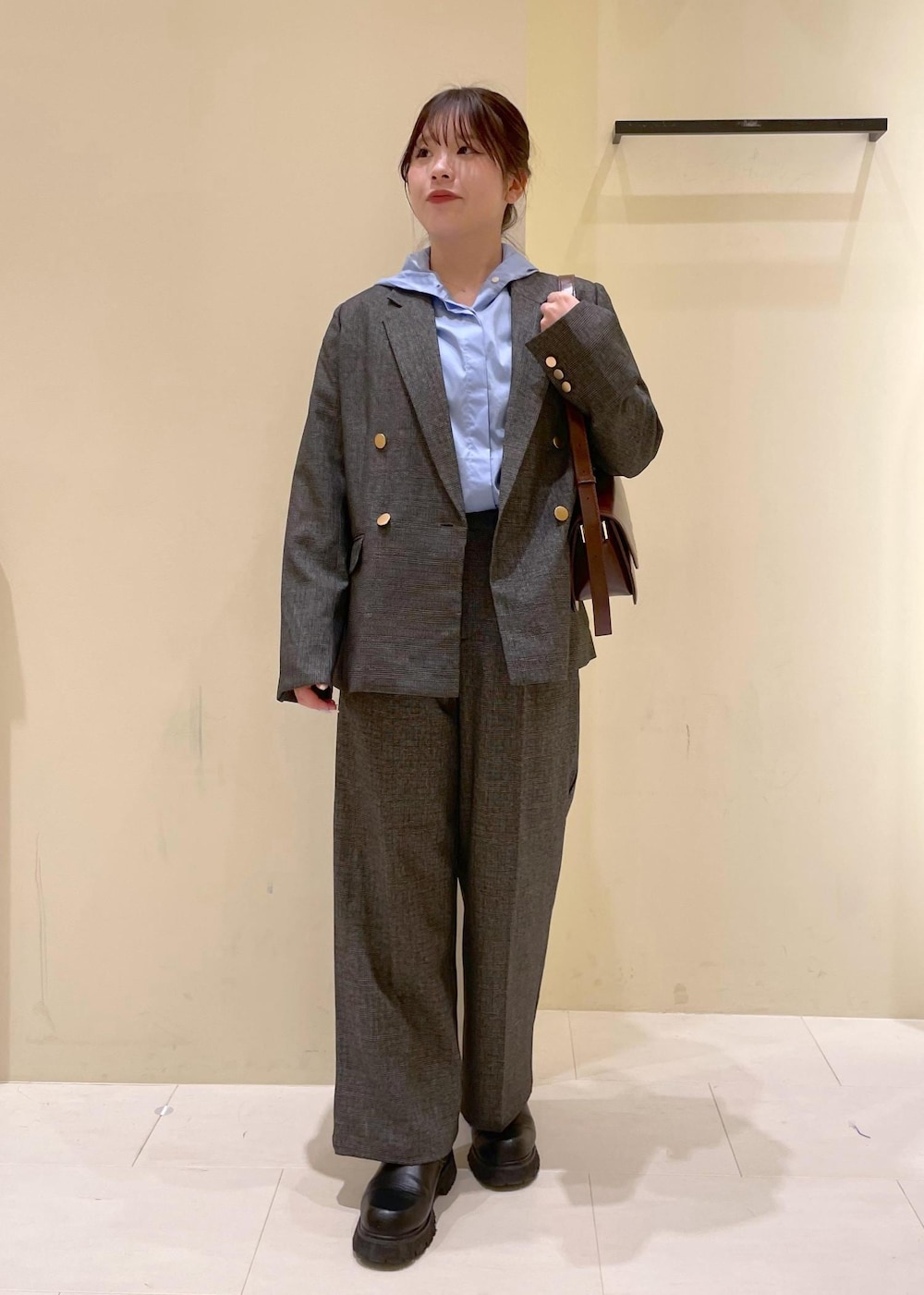 レッド系のショルダーバッグ、グレー系のテーラードジャケット、グレー系のスラックスを着用したレディースの秋コーディネートの5枚目の写真