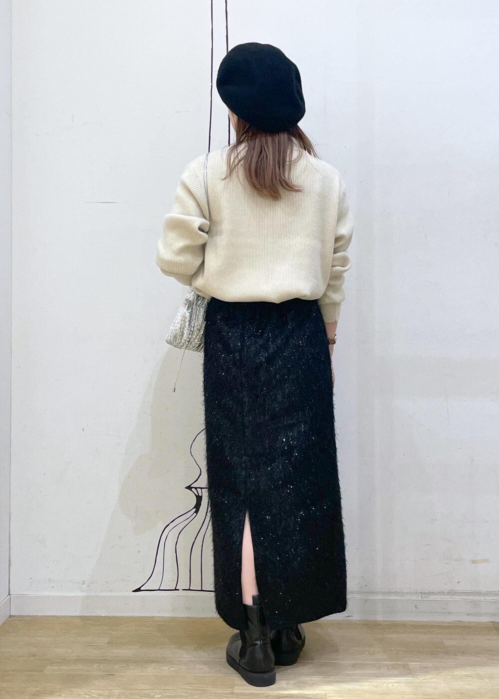 ブラック系のスカート、ベージュ系のニット/セーター、ブラック系のブーツを着用したレディースの冬コーディネートの2枚目の写真