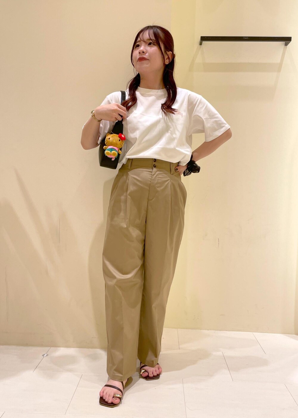 ベージュ系のチノパンツ、ブラウン系のサンダル、ブラック系のハンドバッグを着用したレディースの夏コーディネートの4枚目の写真