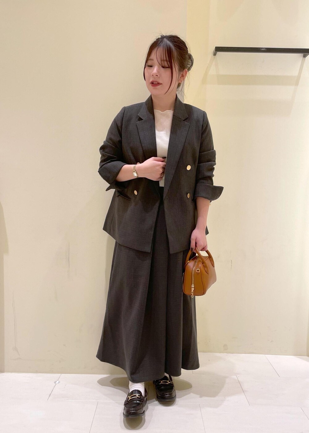 ブラック系のスカート、ブラック系のテーラードジャケット、ベージュ系のTシャツ/カットソーを着用したレディースの秋コーディネートの2枚目の写真