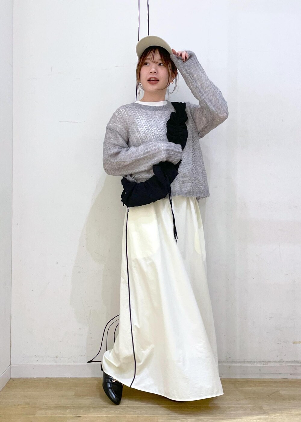 ブラック系のローファー、ホワイト系のスカート、グレー系のニット/セーターを着用したレディースの秋コーディネートの4枚目の写真