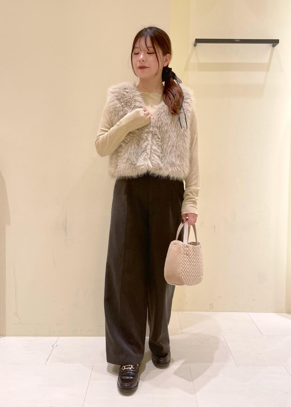 ブラック系のスラックス、ベージュ系のTシャツ/カットソー、ベージュ系のベストを着用したレディースの秋コーディネートの10枚目の写真