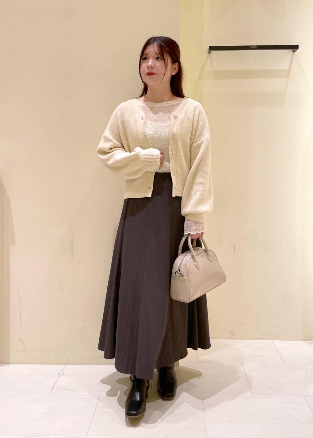 グレー系のスカート、ホワイト系のカーディガン/ボレロ、ホワイト系のTシャツ/カットソーを着用したレディースの秋コーディネートの4枚目の写真