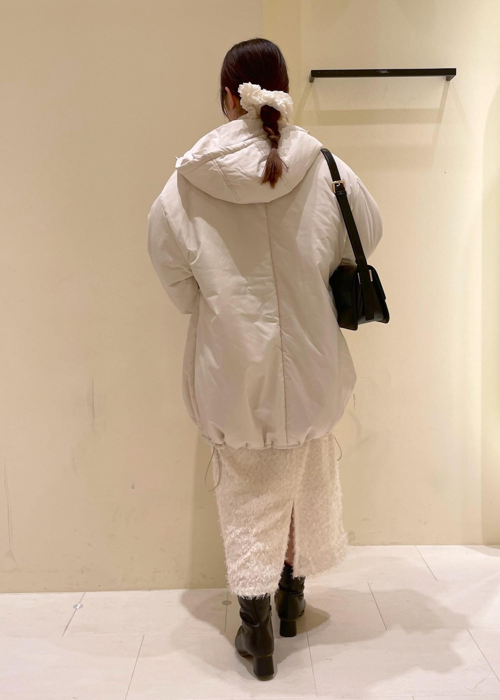 ブラック系のショルダーバッグ、ホワイト系のニット/セーター、ブラック系のブーツを着用したレディースの秋コーディネートの3枚目の写真