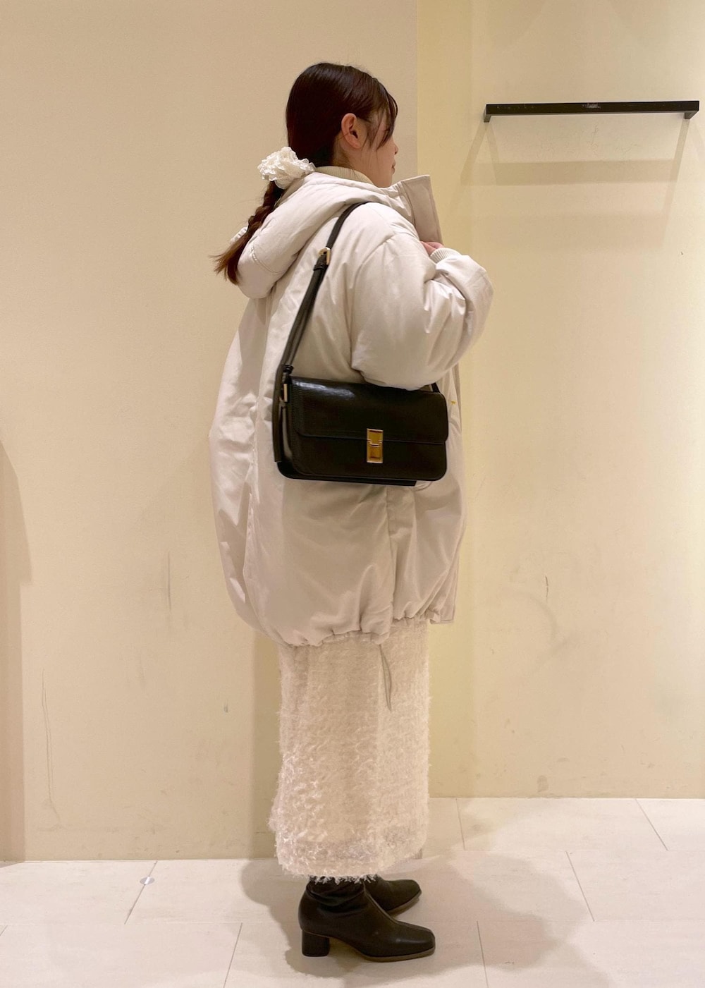 ブラック系のショルダーバッグ、ホワイト系のニット/セーター、ブラック系のブーツを着用したレディースの秋コーディネートの2枚目の写真