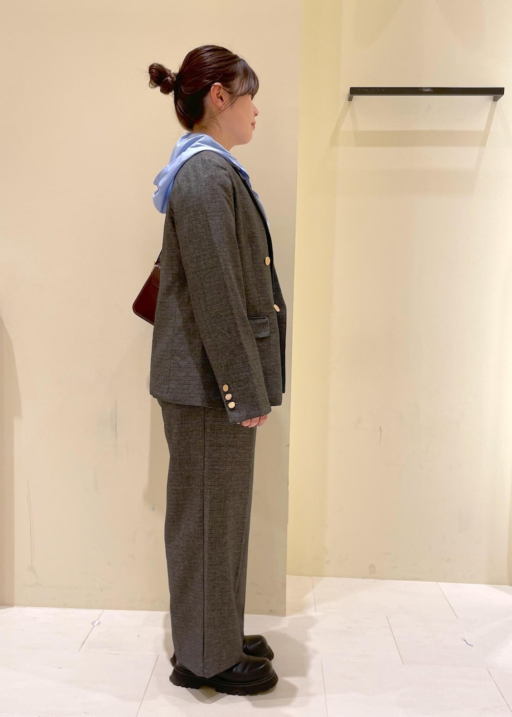 レッド系のショルダーバッグ、グレー系のテーラードジャケット、グレー系のスラックスを着用したレディースの秋コーディネートの2枚目の写真