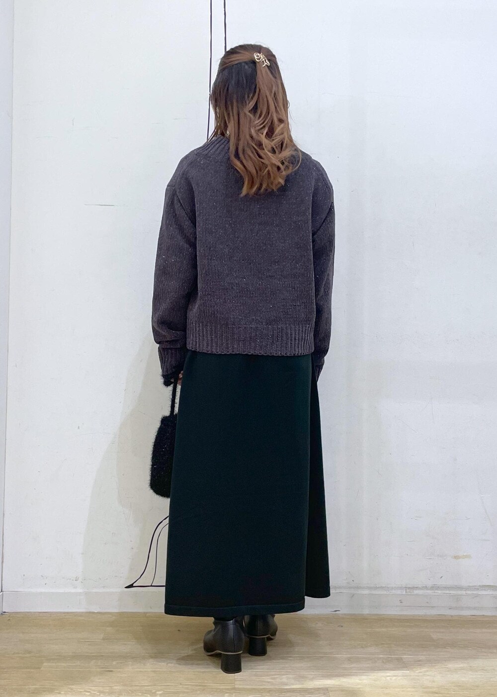 ブラック系のワンピース、グレー系のニット/セーター、ブラック系のブーツを着用したレディースの冬コーディネートの2枚目の写真