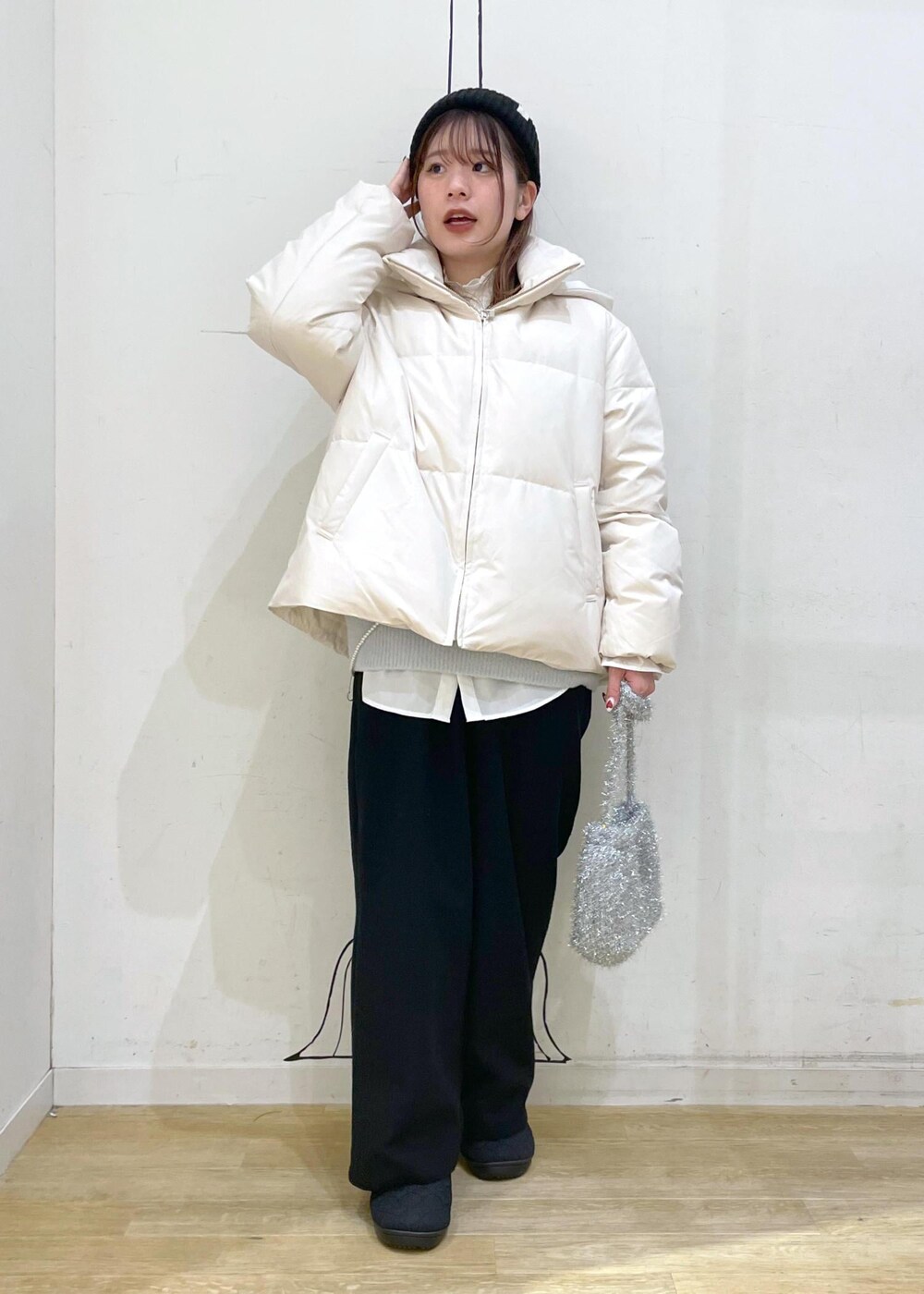 ベージュ系のダウンジャケット/コート、シルバー系のショルダーバッグ、ブルー系のニット/セーターを着用したレディースの冬コーディネートの4枚目の写真