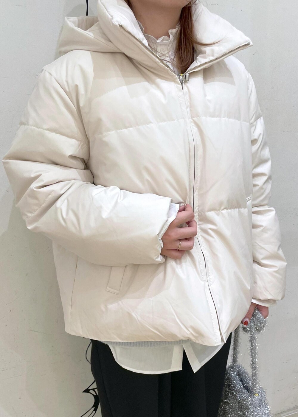 ベージュ系のダウンジャケット/コート、シルバー系のショルダーバッグ、ブルー系のニット/セーターを着用したレディースの冬コーディネートの5枚目の写真