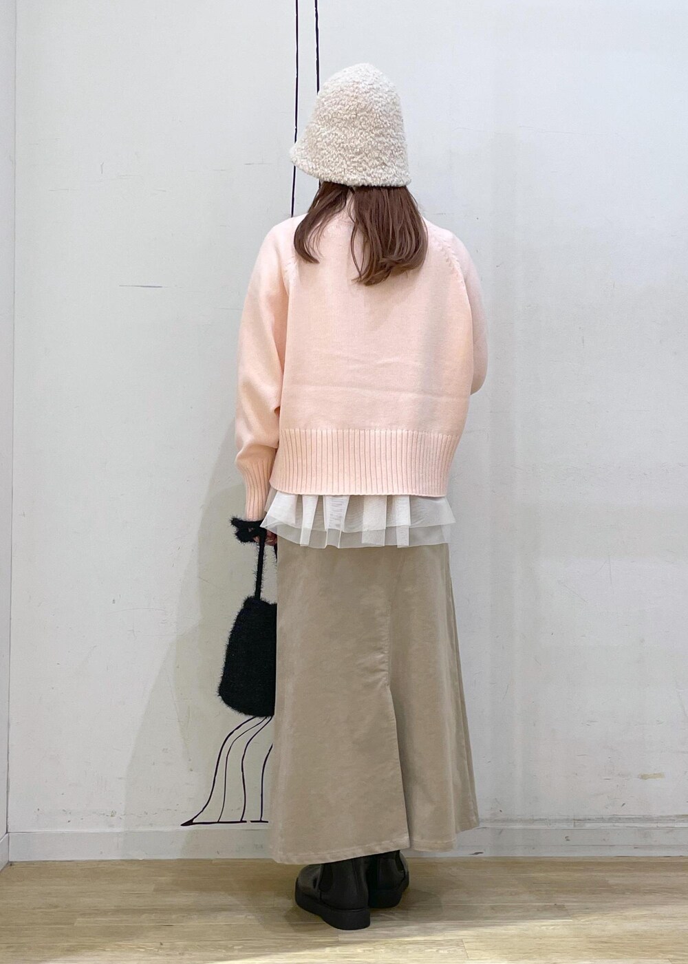 ピンク系のニット/セーター、ブラック系のブーツ、ブラック系のショルダーバッグを着用したレディースの冬コーディネートの2枚目の写真