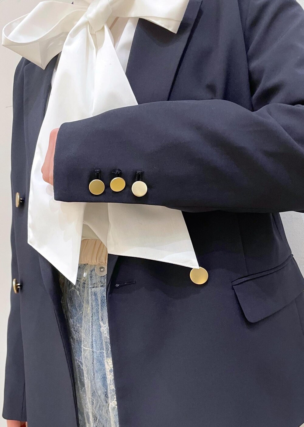 ブルー系のデニムパンツ、ホワイト系のスカート、シルバー系のハンドバッグを着用したレディースの冬コーディネートの6枚目の写真