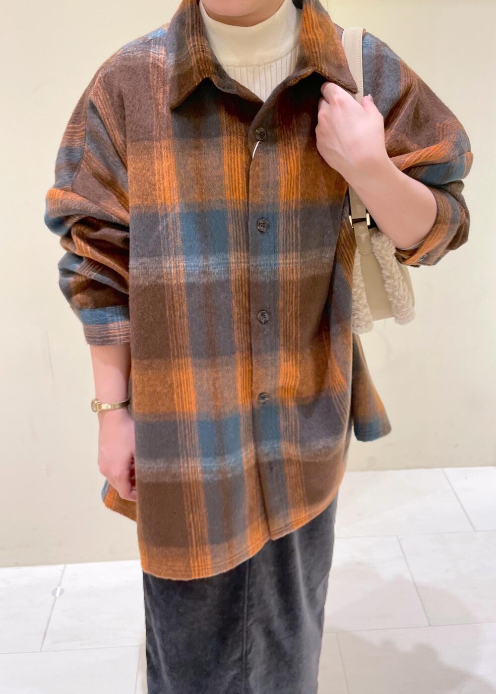ホワイト系のニット/セーター、ベージュ系のショルダーバッグ、オレンジ系のシャツ/ブラウスを着用したレディースの冬コーディネートの5枚目の写真