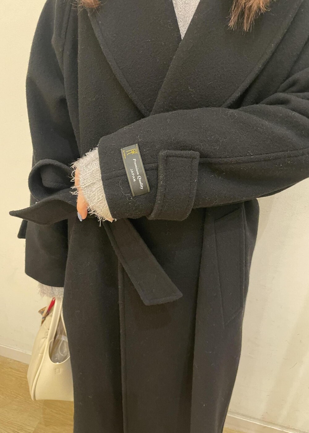 ブラウン系のローファー、グレー系のスカート、ブラック系のチェスターコートを着用したレディースの冬コーディネートの7枚目の写真