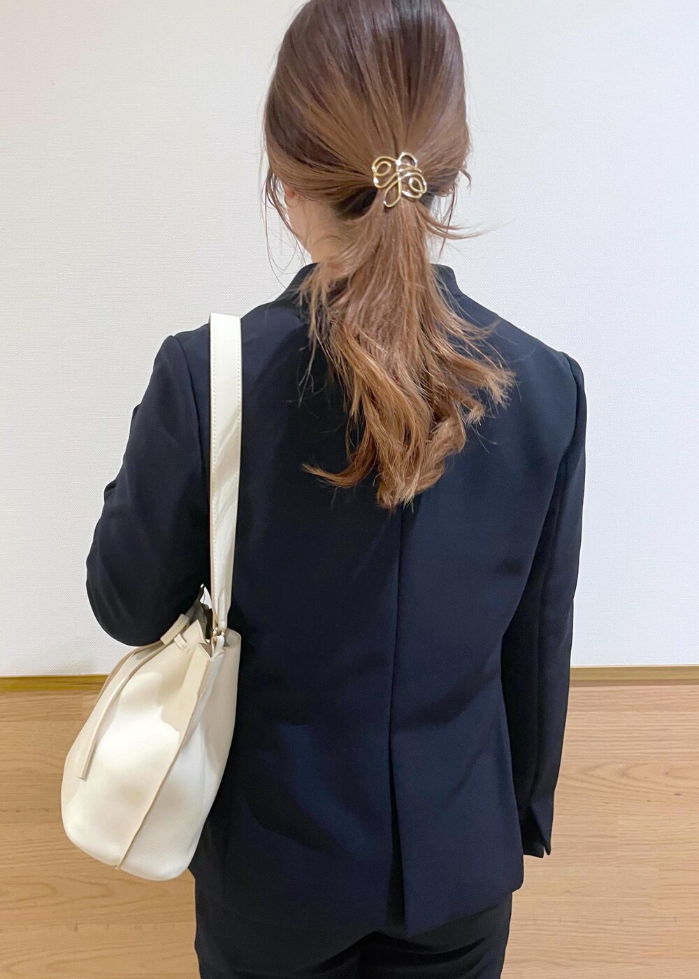ホワイト系のハンドバッグ、ブラック系のパンプス、ブルー系のノーカラージャケットを着用したレディースの春コーディネートの6枚目の写真