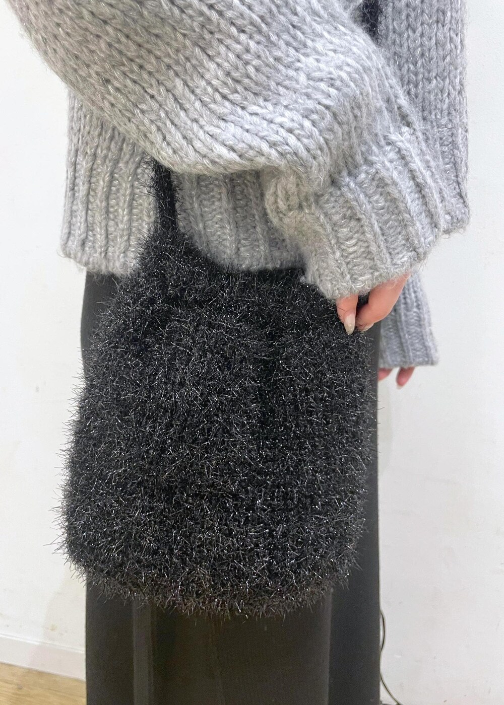 ブラック系のワンピース、ブラック系のショルダーバッグ、グレー系のニット/セーターを着用したレディースの冬コーディネートの8枚目の写真