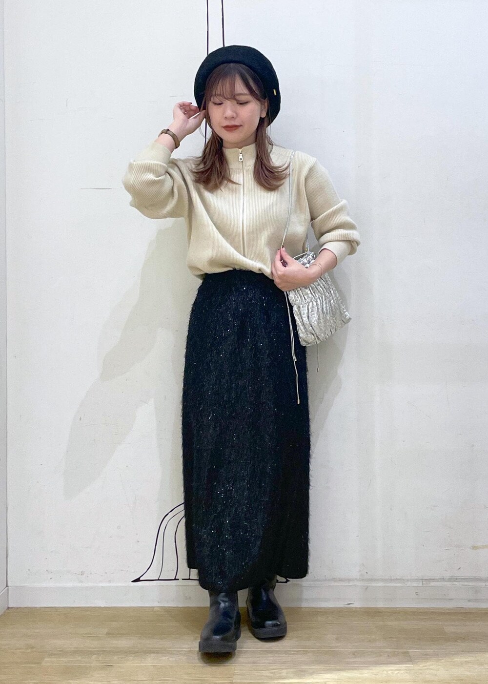 ブラック系のスカート、ベージュ系のニット/セーター、ブラック系のブーツを着用したレディースの冬コーディネートの9枚目の写真