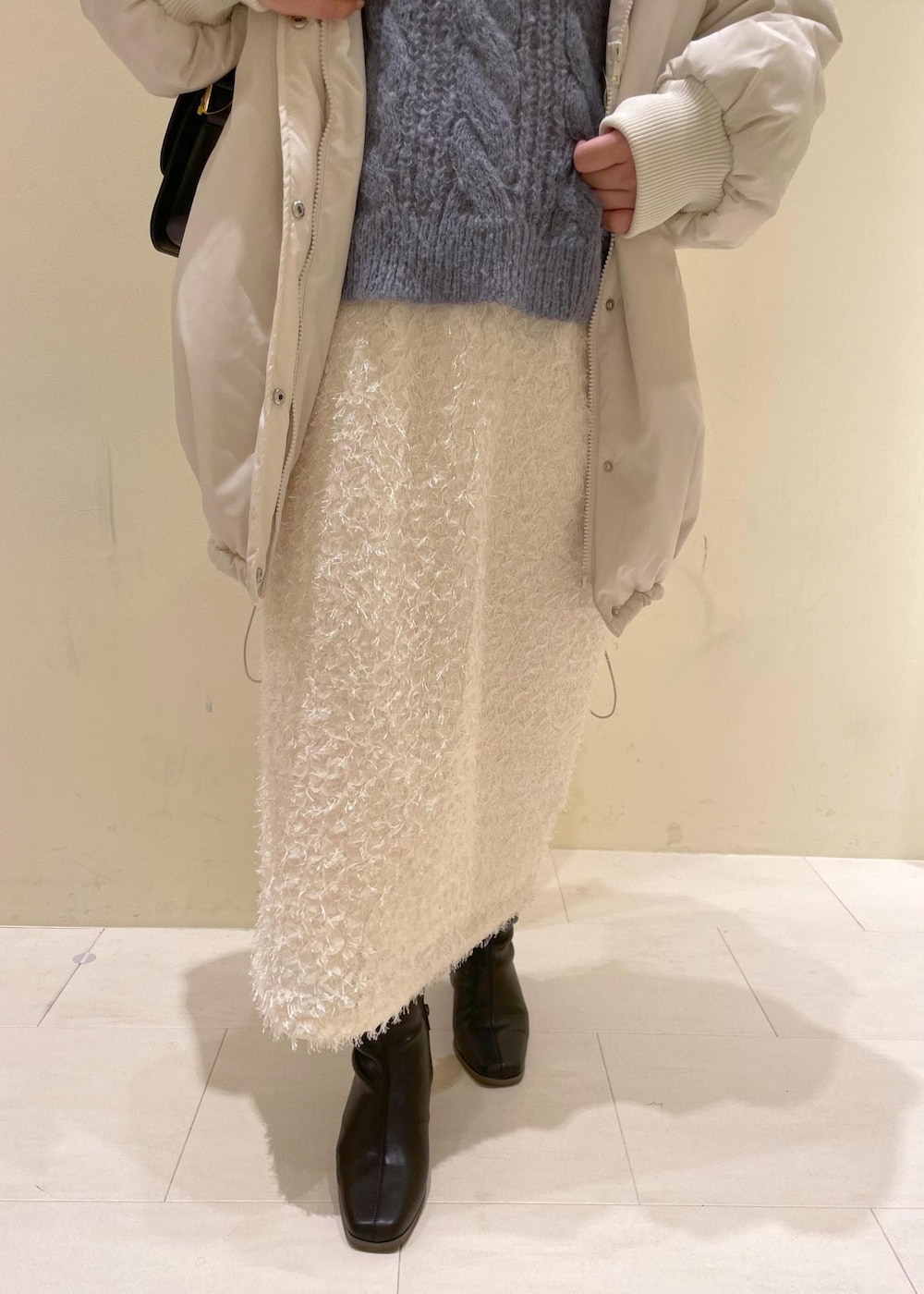 ブラック系のショルダーバッグ、ホワイト系のニット/セーター、ブラック系のブーツを着用したレディースの秋コーディネートの6枚目の写真