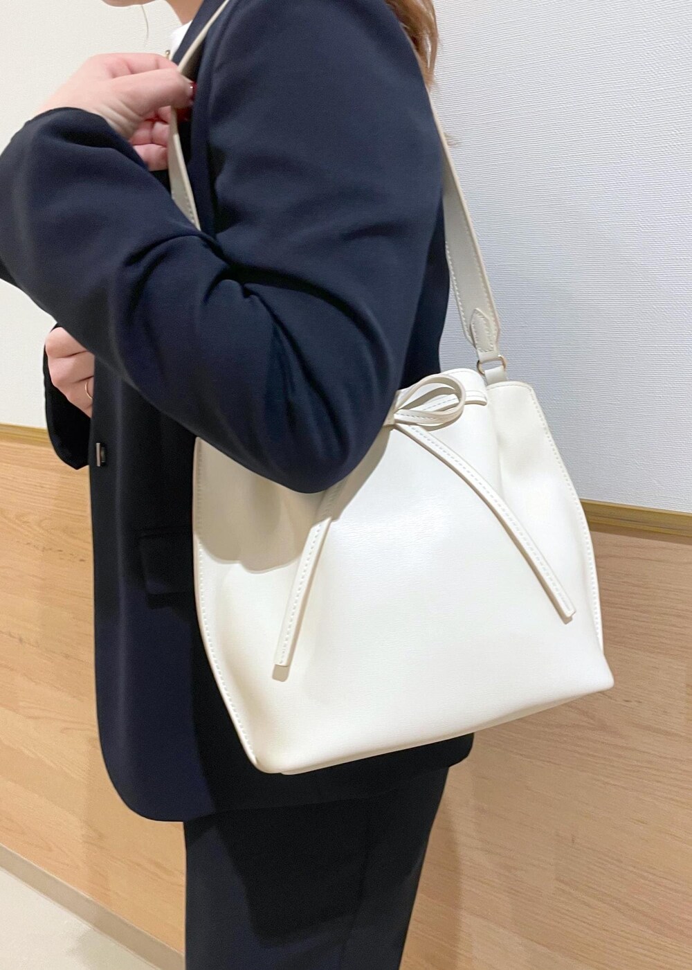 ホワイト系のハンドバッグ、ブラック系のパンプス、ブルー系のノーカラージャケットを着用したレディースの春コーディネートの7枚目の写真