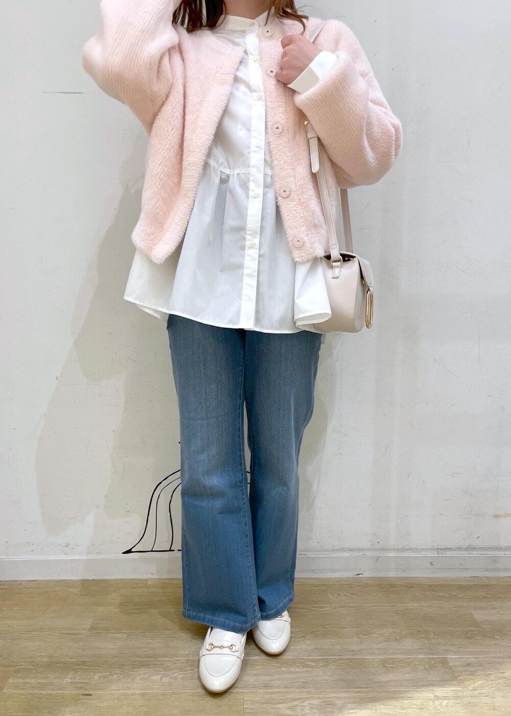 ブルー系のデニムパンツ、ホワイト系のショルダーバッグ、ホワイト系のパンプスを着用したレディースの冬コーディネートの6枚目の写真