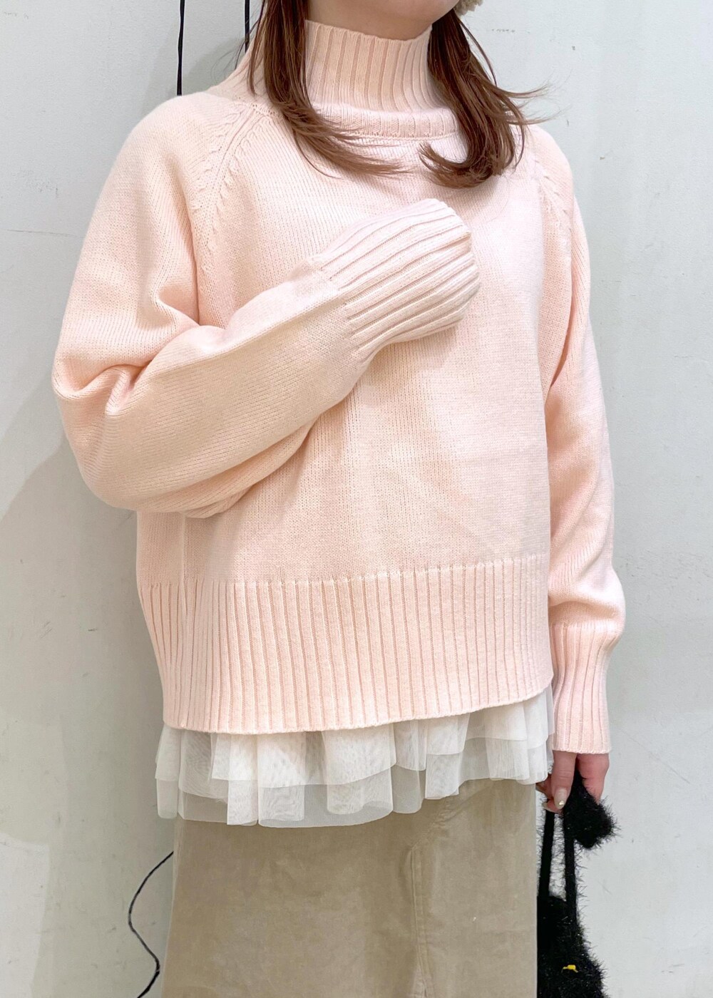 ピンク系のニット/セーター、ブラック系のブーツ、ブラック系のショルダーバッグを着用したレディースの冬コーディネートの8枚目の写真