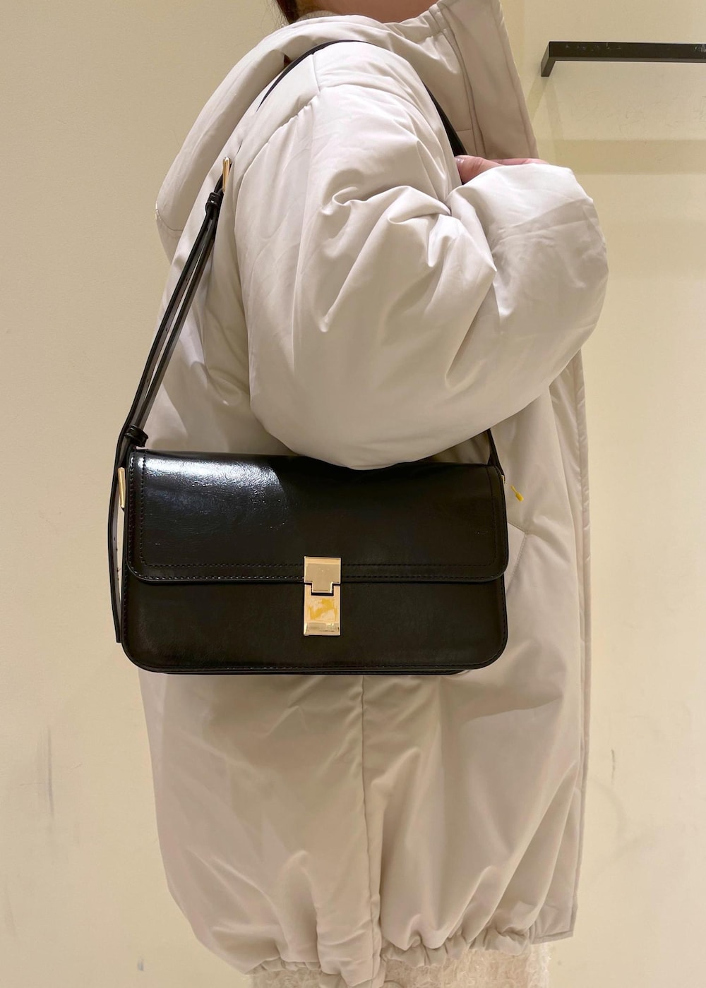 ブラック系のショルダーバッグ、ホワイト系のニット/セーター、ブラック系のブーツを着用したレディースの秋コーディネートの7枚目の写真