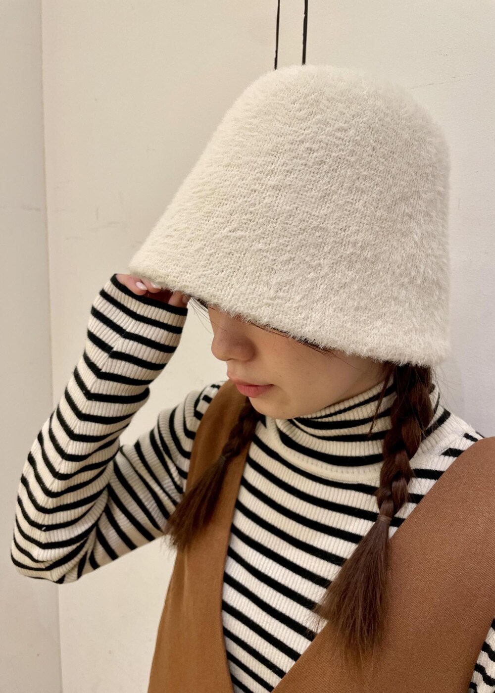 ホワイト系のニット/セーター、ブラウン系のジャンパースカート、ブラック系のローファーを着用したレディースの冬コーディネートの6枚目の写真