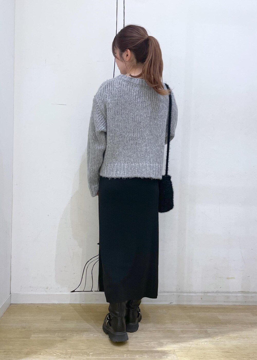 ブラック系のワンピース、ブラック系のショルダーバッグ、グレー系のニット/セーターを着用したレディースの冬コーディネートの2枚目の写真