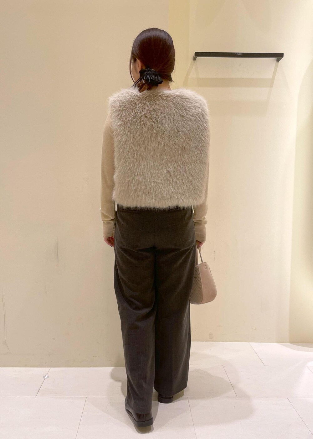 ブラック系のスラックス、ベージュ系のTシャツ/カットソー、ベージュ系のベストを着用したレディースの秋コーディネートの2枚目の写真