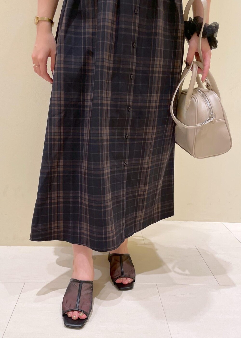 ブラック系のパンプス、ブラック系のワンピース、ベージュ系のボストンバッグを着用したレディースの夏コーディネートの6枚目の写真