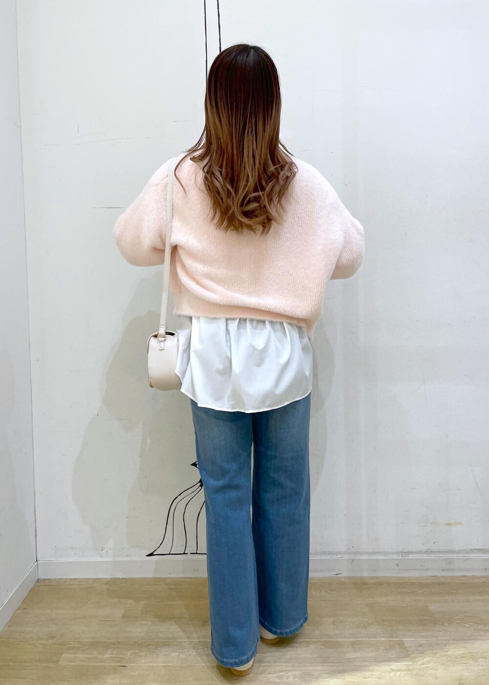 ブルー系のデニムパンツ、ホワイト系のショルダーバッグ、ホワイト系のパンプスを着用したレディースの冬コーディネートの2枚目の写真