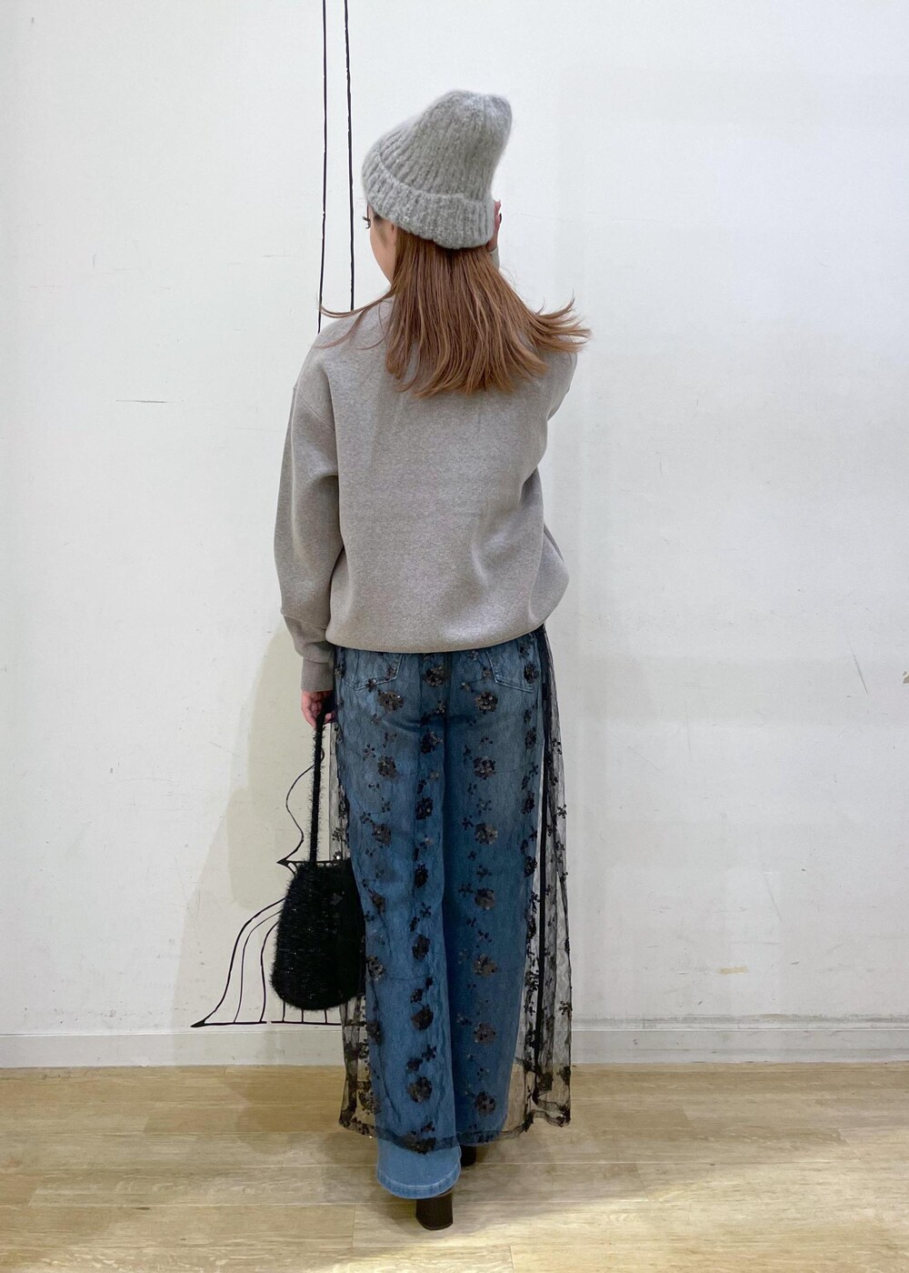 ブラック系のスカート、グレー系のニット/セーター、ブラック系のブーツを着用したレディースの秋コーディネートの2枚目の写真