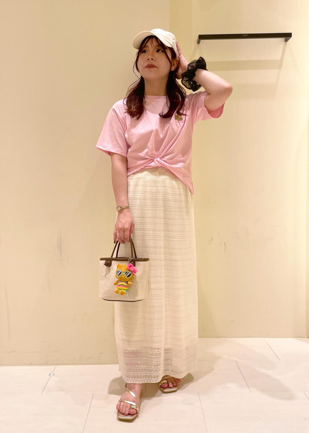 ホワイト系のスカート、ゴールド系のサンダル、ブラウン系のトートバッグを着用したレディースの夏コーディネートの2枚目の写真