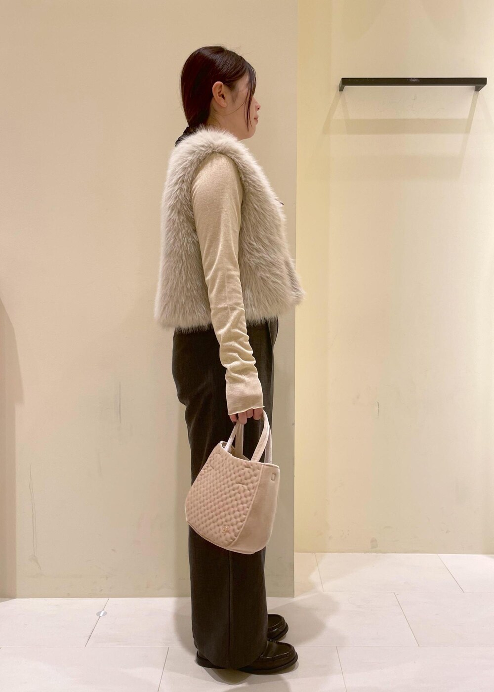 ブラック系のスラックス、ベージュ系のTシャツ/カットソー、ベージュ系のベストを着用したレディースの秋コーディネートの3枚目の写真