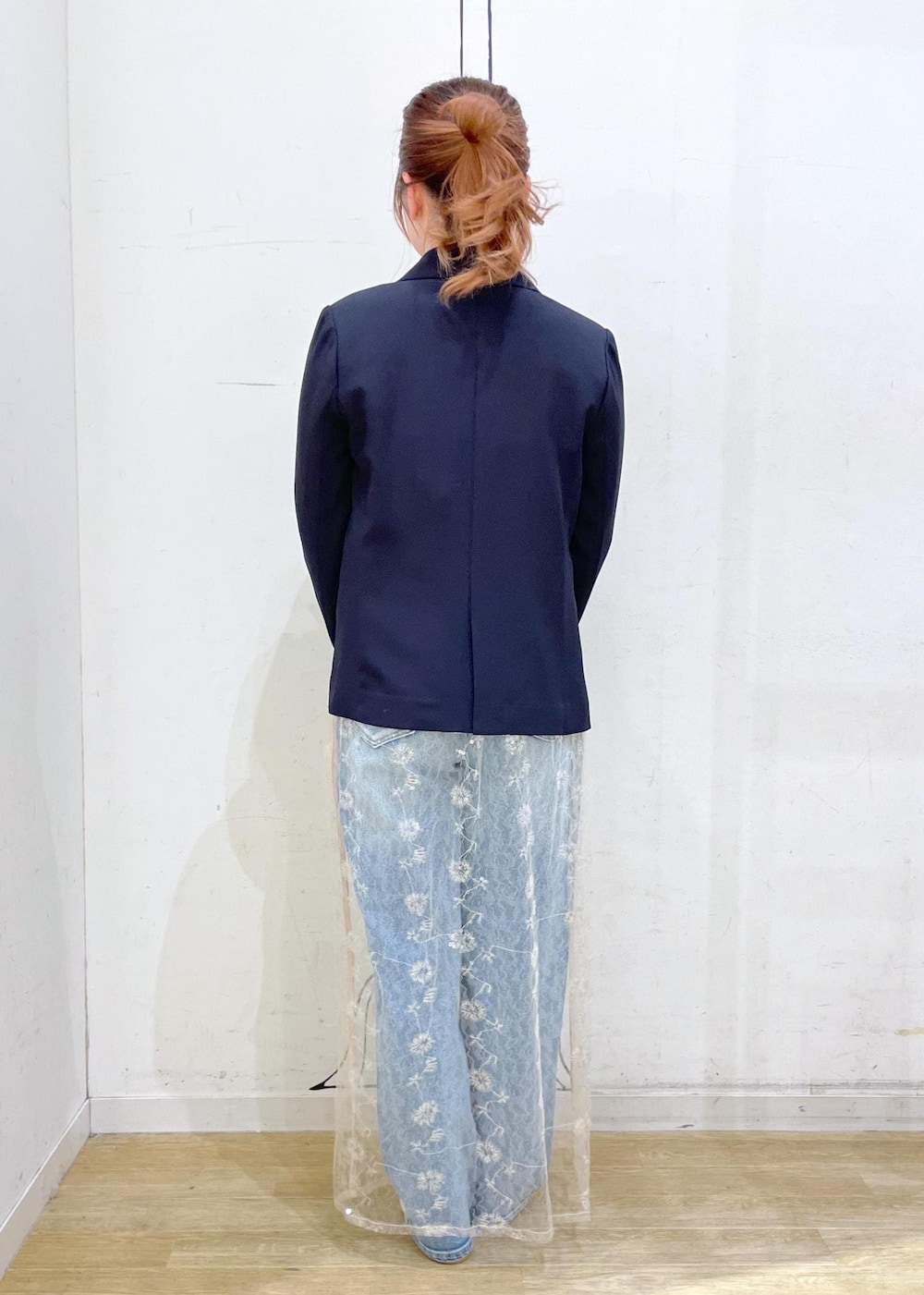 ブルー系のデニムパンツ、ホワイト系のスカート、シルバー系のハンドバッグを着用したレディースの冬コーディネートの2枚目の写真