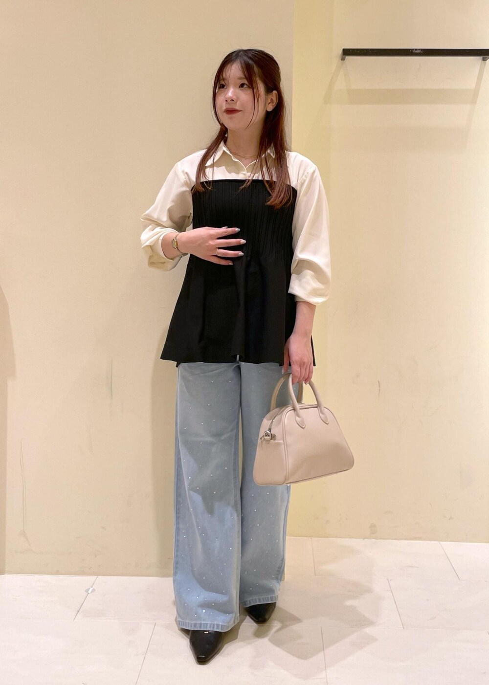 ブルー系のデニムパンツ、ベージュ系のボストンバッグ、ブラック系のパンプスを着用したレディースの秋コーディネートの4枚目の写真