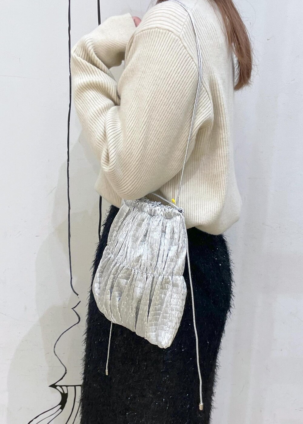 ブラック系のスカート、ベージュ系のニット/セーター、ブラック系のブーツを着用したレディースの冬コーディネートの6枚目の写真