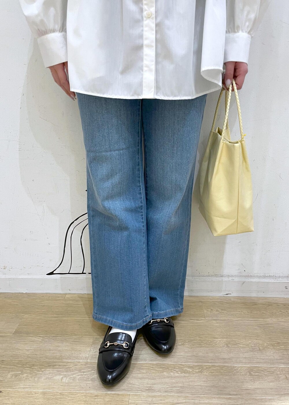 ブラック系のベスト、ブルー系のデニムパンツ、イエロー系のトートバッグを着用したレディースの冬コーディネートの7枚目の写真