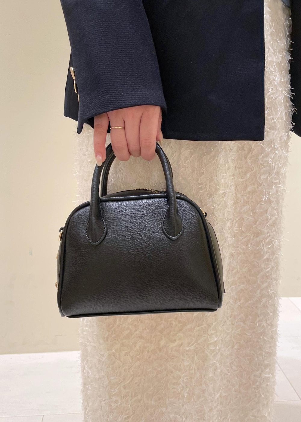 ブラック系のショルダーバッグ、ホワイト系のスカート、ブラック系のローファーを着用したレディースの秋コーディネートの9枚目の写真