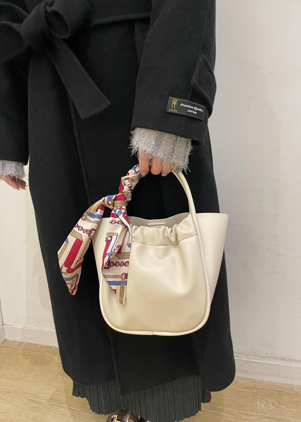 ブラウン系のローファー、グレー系のスカート、ブラック系のチェスターコートを着用したレディースの冬コーディネートの6枚目の写真