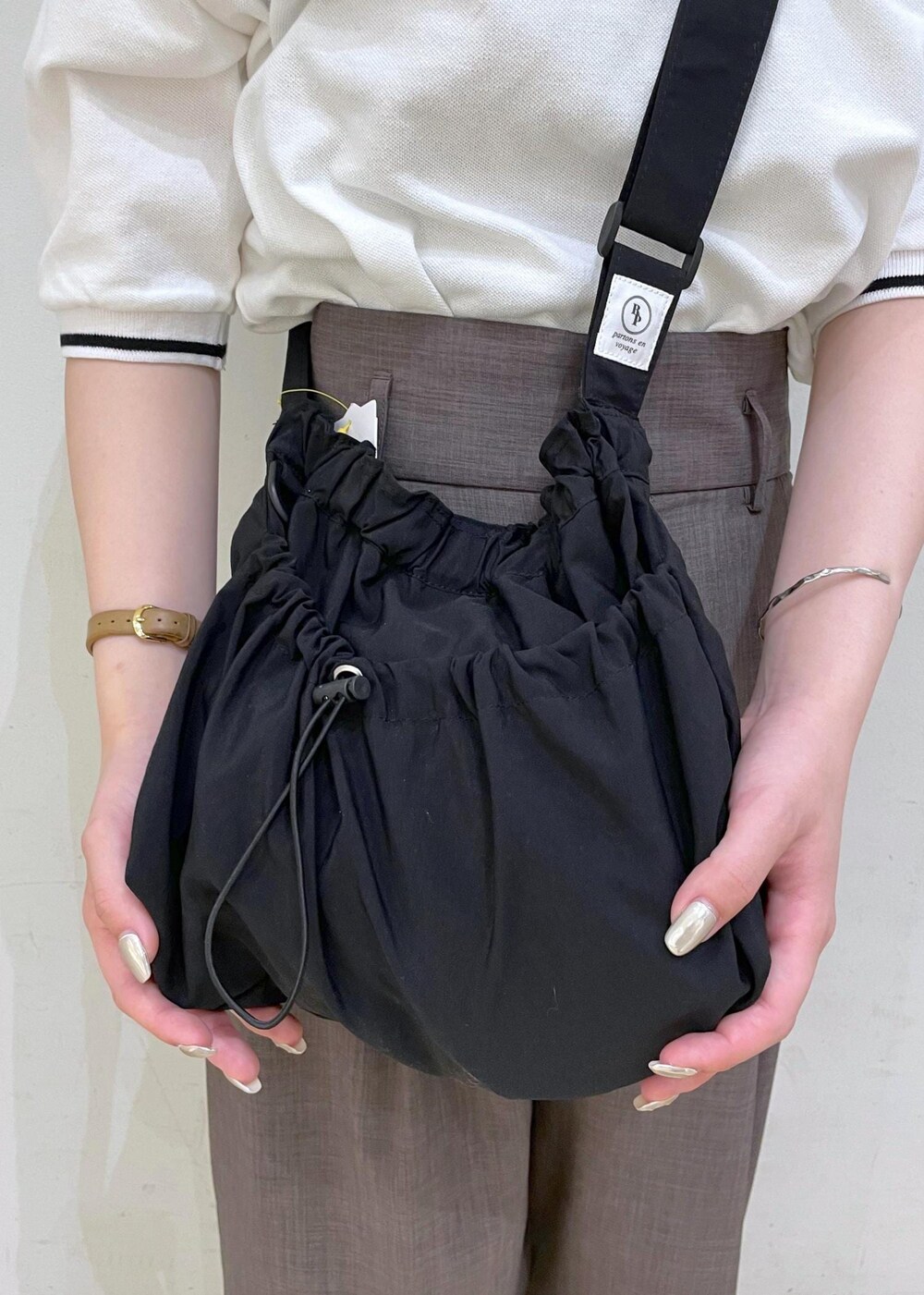 ブラウン系のその他パンツ、ブラック系のサンダル、ホワイト系のポロシャツを着用したレディースの春コーディネートの7枚目の写真