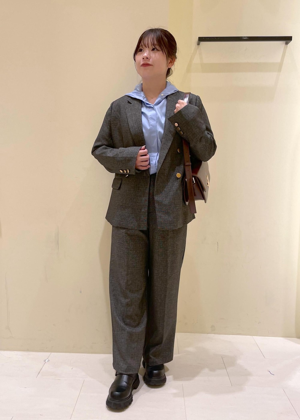 レッド系のショルダーバッグ、グレー系のテーラードジャケット、グレー系のスラックスを着用したレディースの秋コーディネートの4枚目の写真
