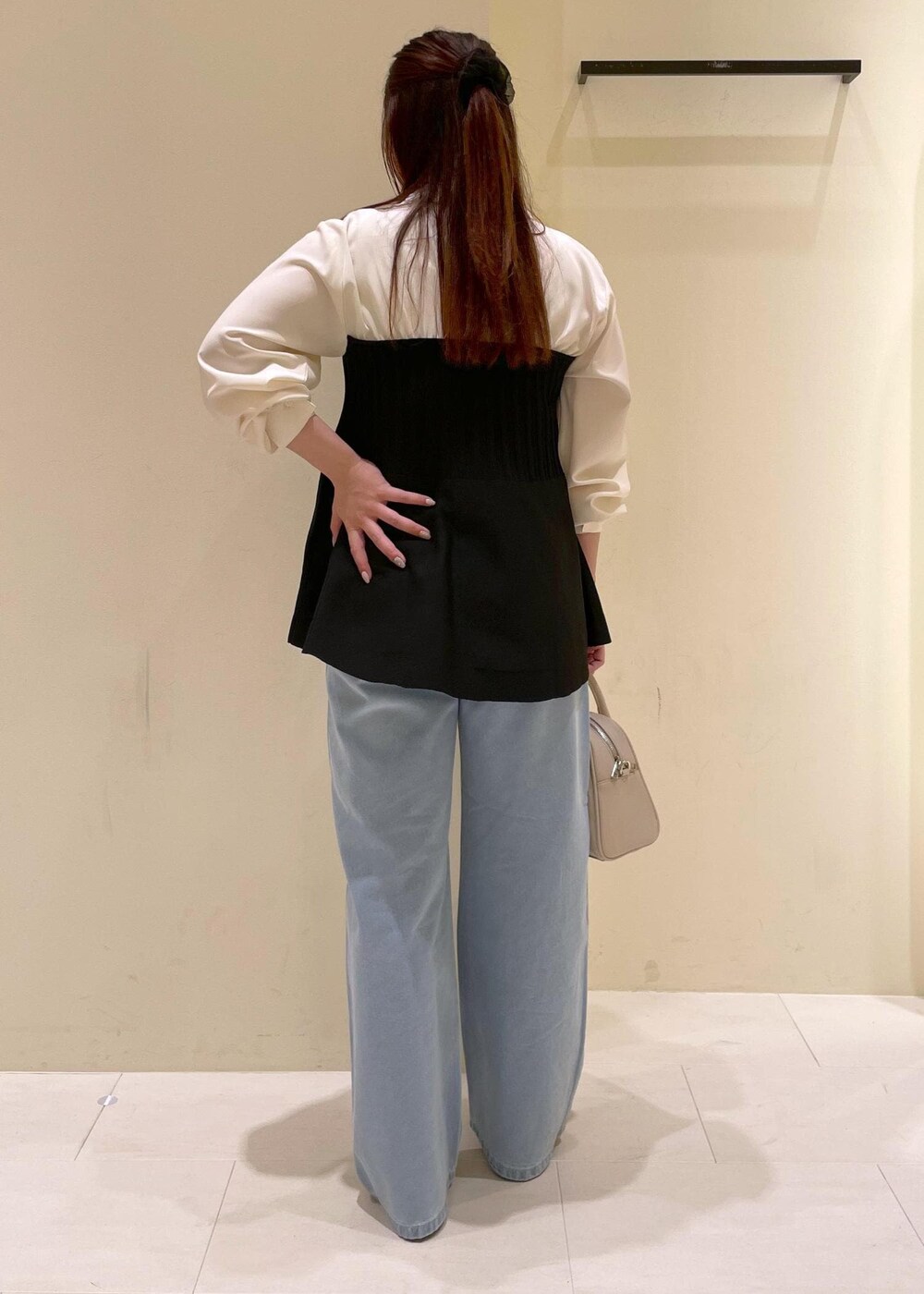 ブルー系のデニムパンツ、ベージュ系のボストンバッグ、ブラック系のパンプスを着用したレディースの秋コーディネートの3枚目の写真