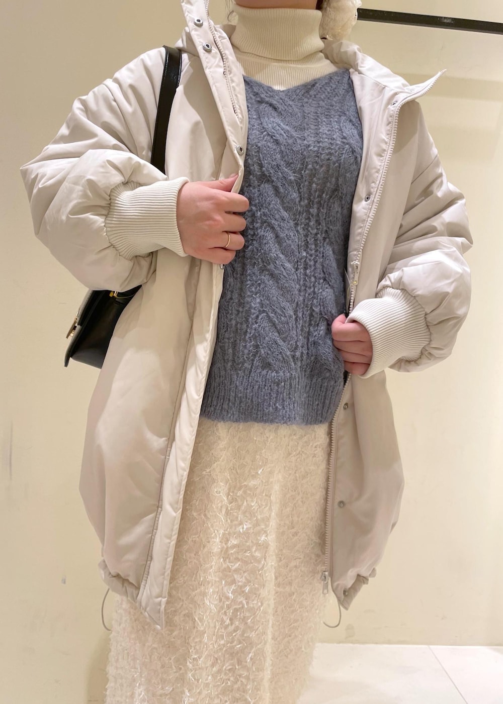 ブラック系のショルダーバッグ、ホワイト系のニット/セーター、ブラック系のブーツを着用したレディースの秋コーディネートの5枚目の写真