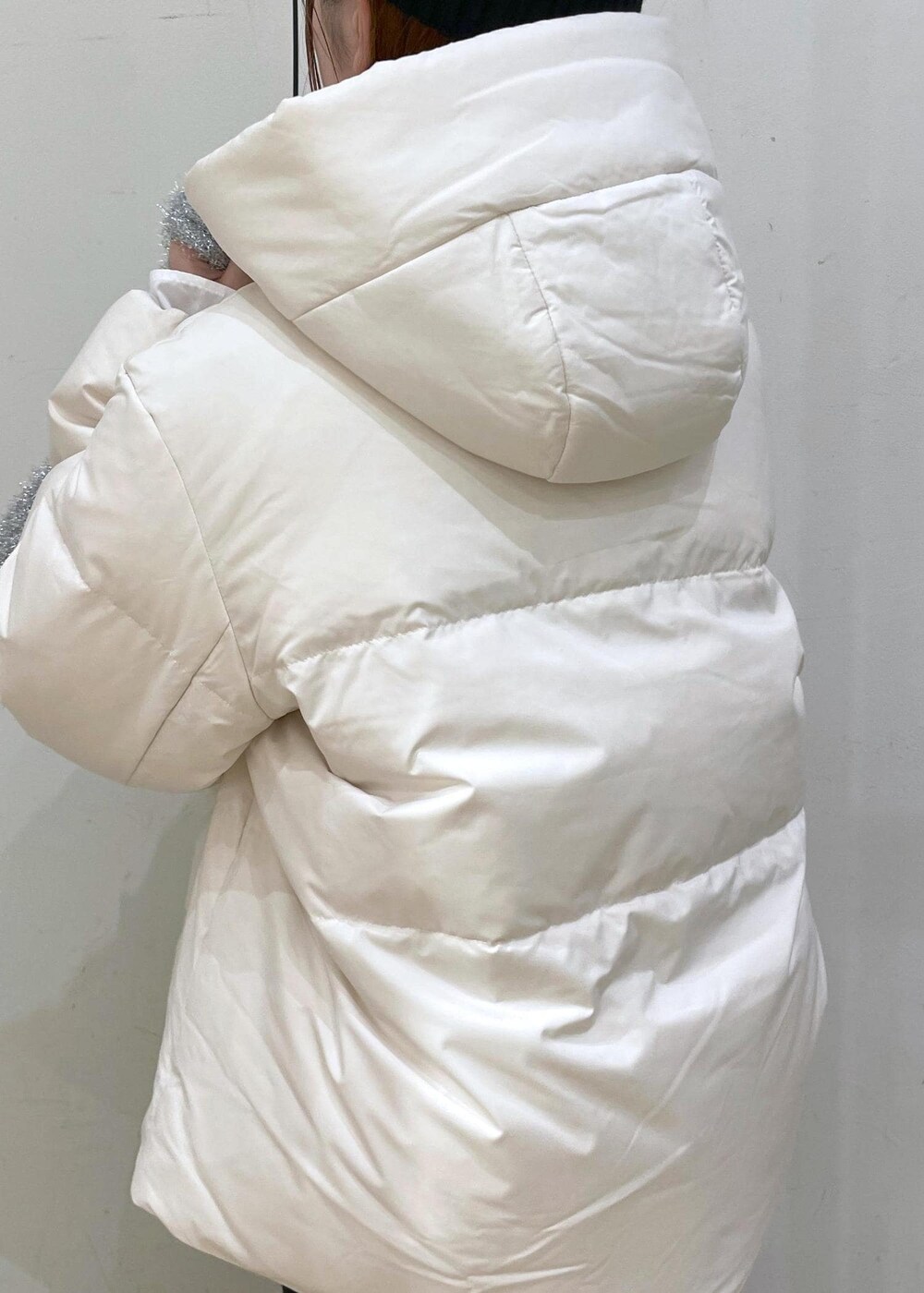 ベージュ系のダウンジャケット/コート、シルバー系のショルダーバッグ、ブルー系のニット/セーターを着用したレディースの冬コーディネートの8枚目の写真