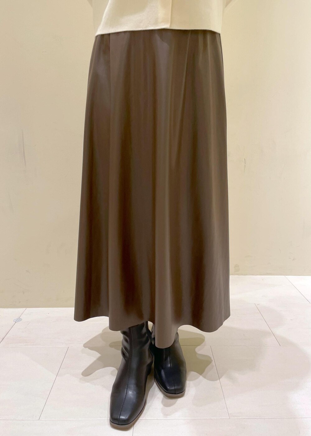 ブラック系のショルダーバッグ、ブラウン系のスカート、ホワイト系のカーディガン/ボレロを着用したレディースの秋コーディネートの7枚目の写真